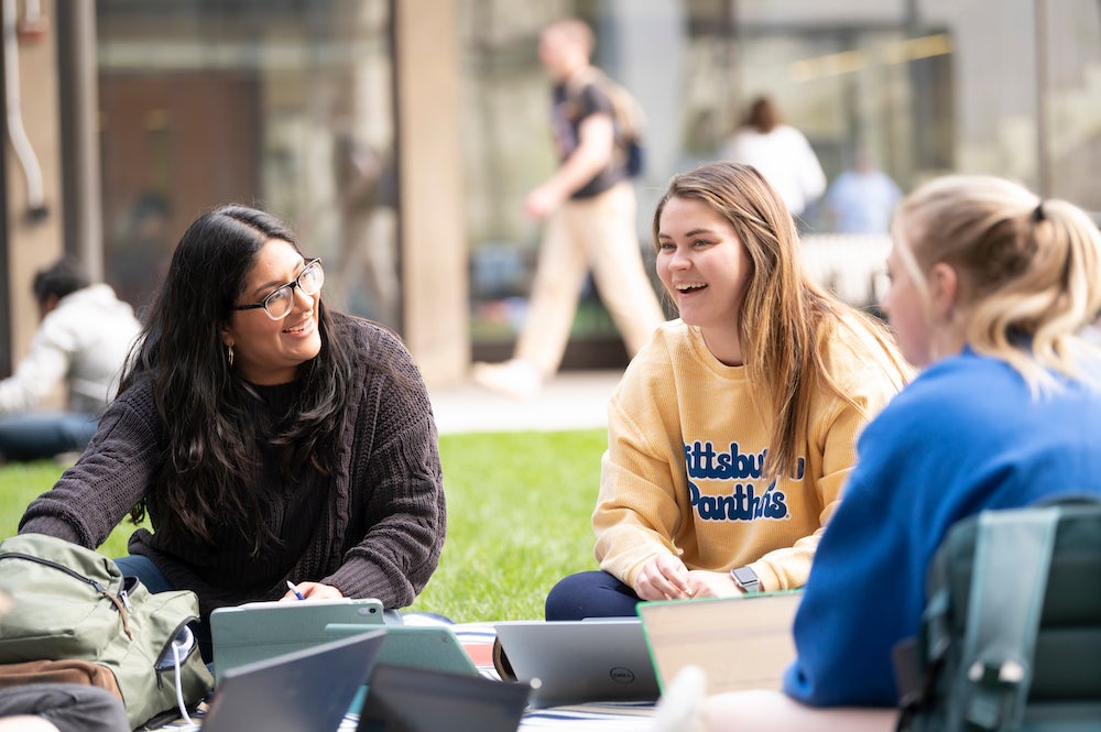 "Three students study together outside"