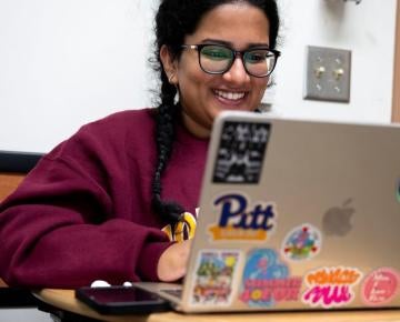 Student smiles while reviewing notes on her laptop