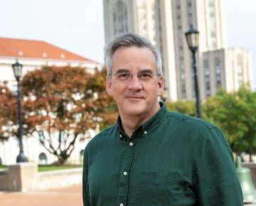 Russ Maiers standing outside in front of the cathedral of learning