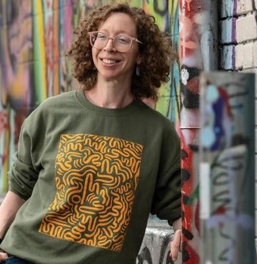 Caitlin Bruce stands in front of a graffiti painted wall