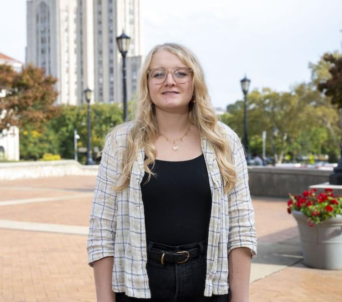 Rachel Clites, woman with blonde hair standing in front of the cathedral of learning