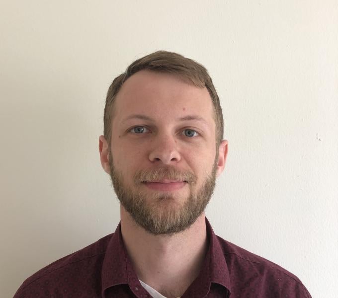 Man with light-colored hair and beard in a burgundy shirt