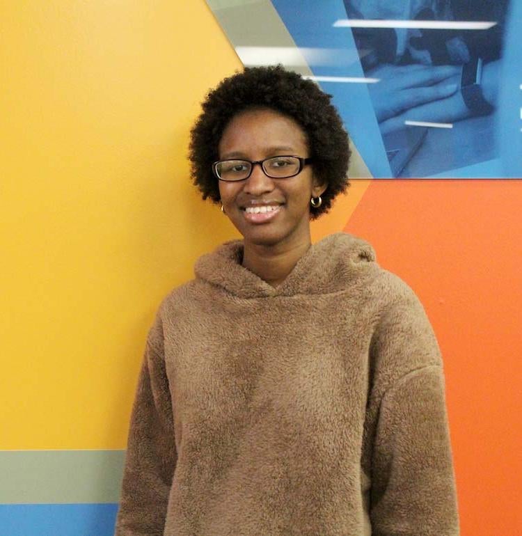 Raby Sylla stands in front of a colorful wall