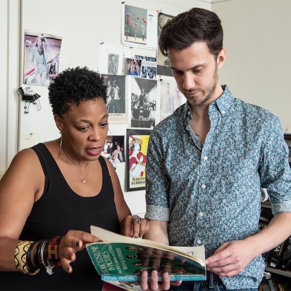 Two students look over a book together. 